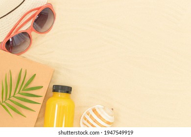 Summer background - sandy beach with accessories for leisure - hat, sungrasses, book, juice