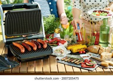 Summer Backyard Picnic. Desk With Electric Grill And Grilled Sausages.