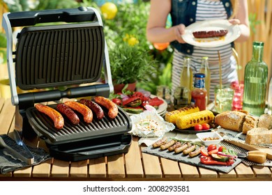 Summer Backyard Picnic. Desk With Electric Grill And Grilled Sausages.