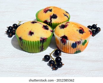 Summer baking - delicious homemade muffins with black currant in colorful paper cups, fresh fruits around