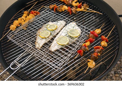 Summer BBQ.  Fish And Vegtables Being Cooked On A Grill Outdoors