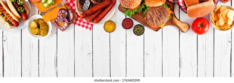 Summer BBQ Food Table Scene With Hot Dog And Hamburger Buffet. Above View Top Border Over A White Wood Banner Background. Copy Space.
