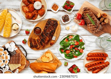 Summer BBQ food table scene over a white wood background. Variety of grilled meats, vegetable dishes and smores platter. Above view. - Powered by Shutterstock