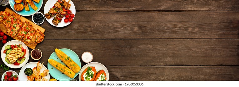 Summer BBQ Grill Corner Border Over A Dark Wood Banner Background. Grilled Flatbread, Chicken And Shrimp Skewers, Stuffed Sweet Potato, Corn, Fruit And Salad. Overhead View With Copy Space.