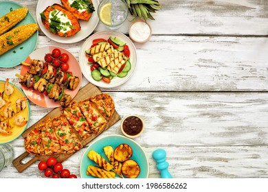 Summer BBQ Grill Side Border Over A White Wood Background. Chicken And Shrimp Skewers, Flatbread, Stuffed Sweet Potato, Grilled Fruit, Corn And Salad. Overhead View With Copy Space.