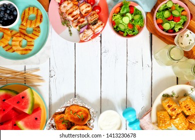 Summer BBQ Or Picnic Food Frame. Selection Of Grilled Meat, Fruits, Salad And Potatoes. Overhead View Over A White Wood Background. Copy Space.