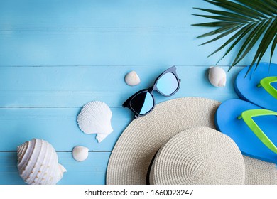 Summer beach background / high angle of the hat Sunglasses and slippers on the blue wooden floor and palm trees with copy space