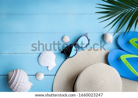 Summer beach background / high angle of the hat Sunglasses and slippers on the blue wooden floor and palm trees with copy space