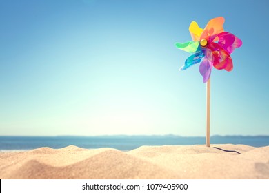 Summer beach background, pinwheel or windmill in the sand concept for vacation copy or message