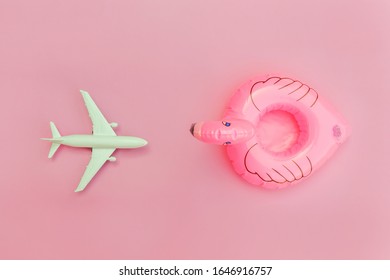 Summer beach composition. Minimal simple flat lay with plane and Inflatable flamingo isolated on pastel pink background. Vacation travel adventure trip concept. Top view copy space