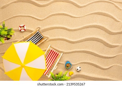 Summer Beach Concept. Sun Loungers, Sun Umbrella And Beach Toys On Yellow Wave Sand. Top View Of Beach.