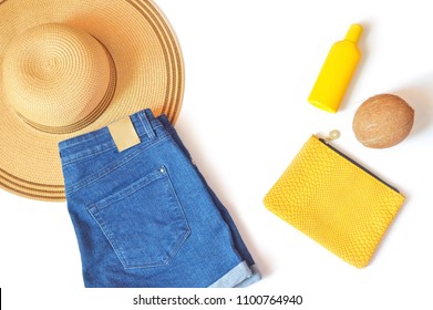 Summer Beach Essentials Flat Lay Photo. Sun Hat, Denim Shorts, Yellow Cosmetic Bag, Sunscreen Bottle And Coconut. Top View Photo