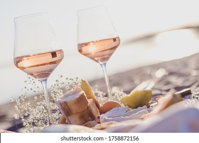 summer beach picnic on the coast with rose wine in glasses, mellon, cheese, bread and fruits on linen tablecloth. romantic party concept. relaxation on summer.