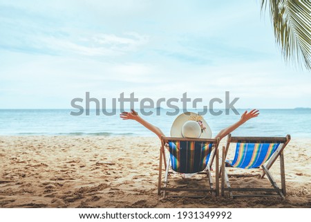 Summer beach travel vacation concept, Happy traveler asian woman with hat relax on chair beach at Pattaya, Chon Buri, Thailand