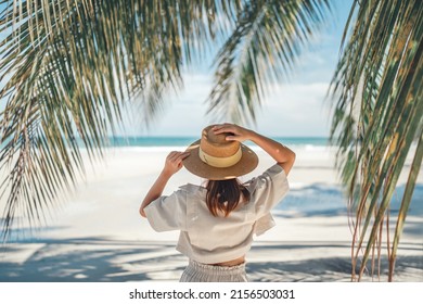 Summer beach vacation concept, Happy woman with hat relaxing at the seaside and looking away, in the summer against a backdrop of palm trees and sea beach. - Powered by Shutterstock
