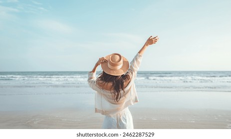 Summer beach vacation concept, Happy young woman with hat relaxing with her arms raised to her head enjoying looking view of beach ocean on hot summer day, copy space - Powered by Shutterstock