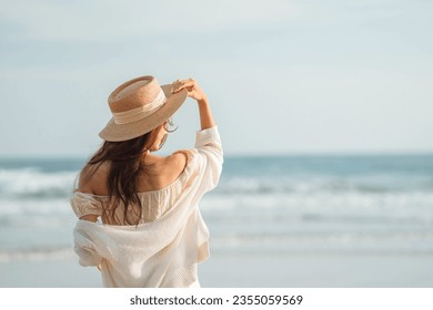 Summer beach vacation concept, Young woman with hat relaxing with her arms raised to her head enjoying looking view of beach ocean on hot summer day, copy space. - Powered by Shutterstock