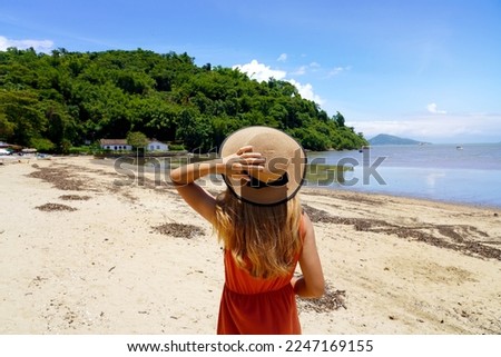 Summer beach vacation. Young woman with hat relaxing enjoying looking view of beach ocean on hot summer day in Brazil.