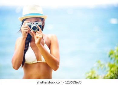 Summer beach woman holding vintage retro camera taking pictures looking at camera during summer holiday vacation travel at the ocean. - Powered by Shutterstock