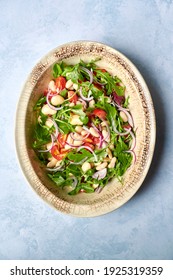 Summer Bean Salad With Cannellini Beans, Salad Leaves, Onions And Tomatoes In An Oval Shaped Vintage Serving Dish Shot From Above