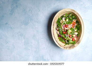 Summer Bean Salad With Cannellini Beans, Salad Leaves, Onions And Tomatoes In An Oval Shaped Serving Dish Shot From Above With Copy Space To Left