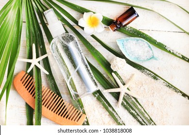 Summer Beauty Care Kit. Bottle Of Mineral Sea Salt Hair And Body Spray Viewed From Above On Green Palm Leaf, Comb, Seastars And Sandy Wooden Background. 