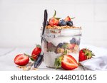 Summer berries granola breakfast layered dessert with yogurt, oat multi grain granola, strawberry, blueberry on wooden table background copy space