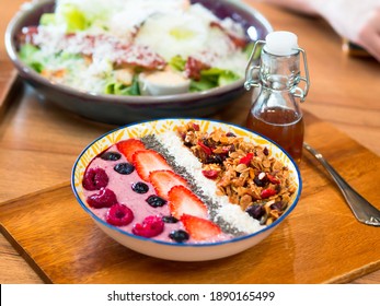 Summer Berries Granola Yogurt breakfast Bowls Colorful tropical nutritious meal with honey bottle on wooden tray for morning needs perfect for healthy snack, dessert, meal replacement. Caesar salad