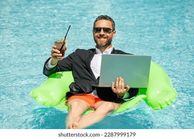 Summer business dreams. Millennial business man in suit floating with cocktail and laptop in swimming pool. Summer vacation. Funny crazy businessman rest in formal wear in pool. Hot summer business.