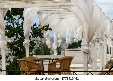 Summer Cafe On The Beach, Brown Wicker Furniture, White Wooden Gazebos, White Curtains Tied To Protect From Strong Wind, Storm