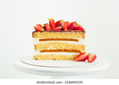 Summer cake decorated with strawberries on the white background. Yellow sponge bisquit cake cut with cream cheese and berry mousse layers