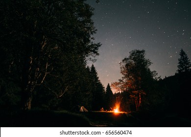 Summer Camp In The Wild Forest At Night With Tent And Campfire.