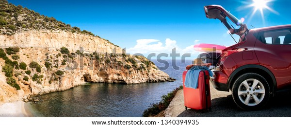Summer car and landscape with sea\
and sun . Red car with suitcase. Free space for your text.\
