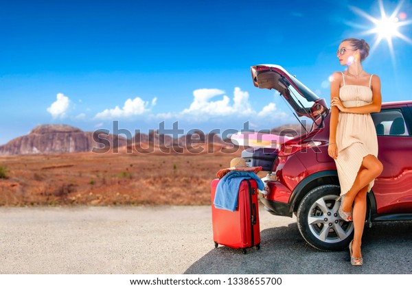 Summer car with suitcase on road in USA and slim young\
woman in summer dress. Free space for your decoration. Summer trip\
of red car. 