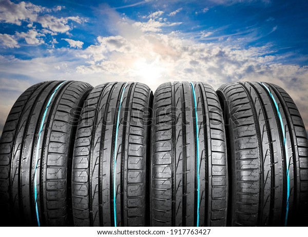 Summer\
car tires on over blue sky with clouds. Tire stack background. Car\
tyre protector close up. Black rubber tire. Brand new car tires.\
Close up black tyre profile. Car tires in a\
row
