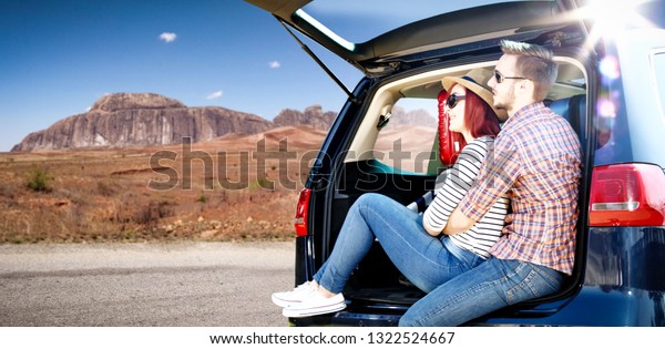 Summer\
car trip on USA road and two oung lovers. Free space for your\
decoration. Blue big car and summer sun light.\
