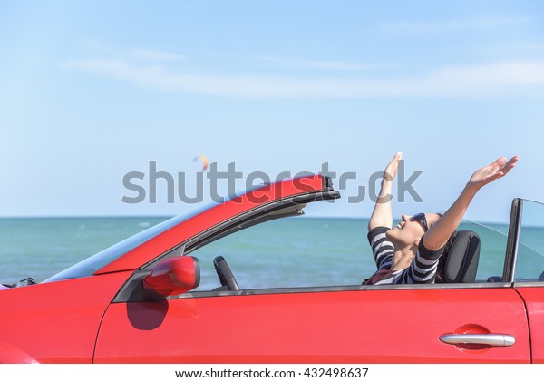 Summer car trip\
vacation . Woman in red car at background of sea water. Travel,\
freedom and holidays\
concept.