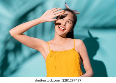 summer casual freshness asian woman yellow summer dress hand rise up to protect sun light shine above,asia woman confident smiling standing studio shot on blue colour background summer concept - Powered by Shutterstock