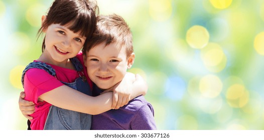 Summer, Childhood, Family, Friendship And People Concept - Two Happy Kids Hugging Over Green Summer Lights Background