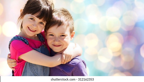 Summer, Childhood, Family, Friendship And People Concept - Two Happy Kids Hugging Over Blue Lights Background