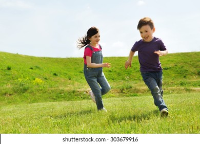summer, childhood, leisure and people concept - happy little boy and girl playing tag game and running outdoors on green field - Powered by Shutterstock