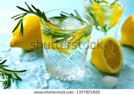 Summer citrus cocktail or lemonade with rosemary in a glasses on a light blue slate, stone or concrete background. Top view with copy space.