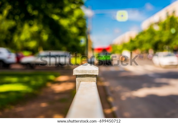 Summer in\
the city, the cars drive down the street with trees. Close up view\
from the handrail on the sidewalk\
level
