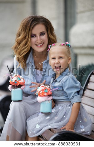 summer city walk of a mother and daughter with milkshakes in beautiful dresses