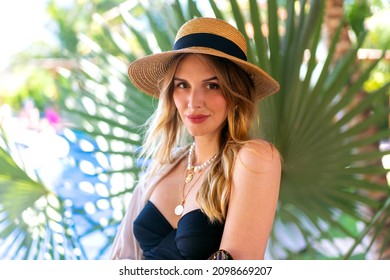 Sommerfoto-Portrait von bezaubernden blonden Frau entspannt sich in ihrem Sommerurlaub in der Nähe von Palmen, trendigen Kleidung und Accessoires.