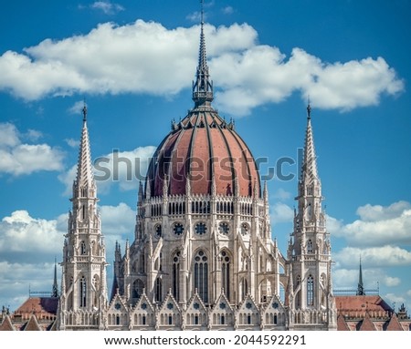 Summer closeup view of the cupola the Hungarian Parliament built in Neo-Gothic style along the Danube river with perfect symmetry with cloudy blue sky