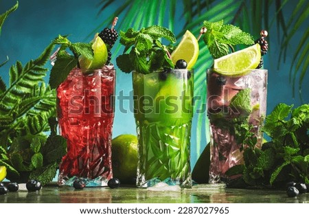 Summer cocktail party.. Refreshing fruit and berry alcoholic cocktails with gin, tequila, vodka, lime, mint and ice, green background