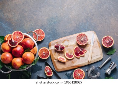 Summer cocktails and fresh orange juice cooking concept. Whole and sliced blood oranges with shaker and bartender utensils over blue table background. Flat lay, top view, copy space
