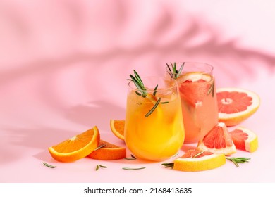 Summer Cocktails With Grapefruit, Orange, Rosemary, And Ice. Drinks On Pink Background With Palm Leaf Shadow. Summer, Tropical, Fresh Cocktail Concept.