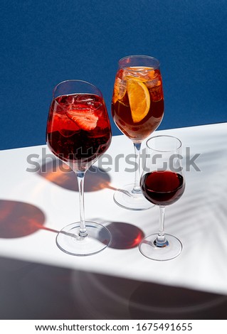Summer cocktails on creative background. Shadows of palm leaf on classic blue wall and white floor. 